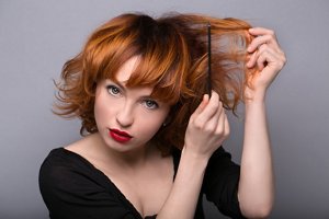 Redheaded woman backcombing her hair